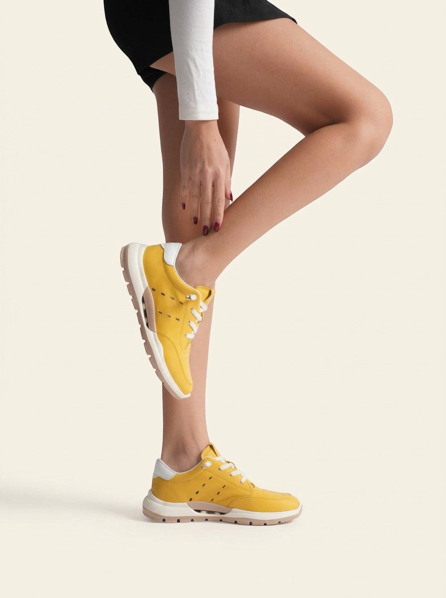 MrCalvano sarı deri sneaker giyen bir model, yan profilden görünüm, beyaz tabanlı ve delikli detaylı günlük spor ayakkabı.